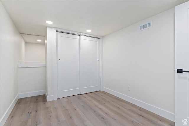unfurnished bedroom with baseboards, light wood-type flooring, recessed lighting, and a closet