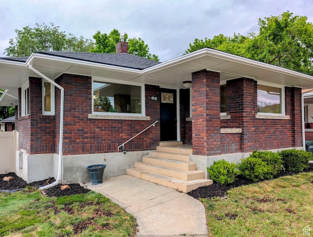 view of front of home with a chimney and brick siding