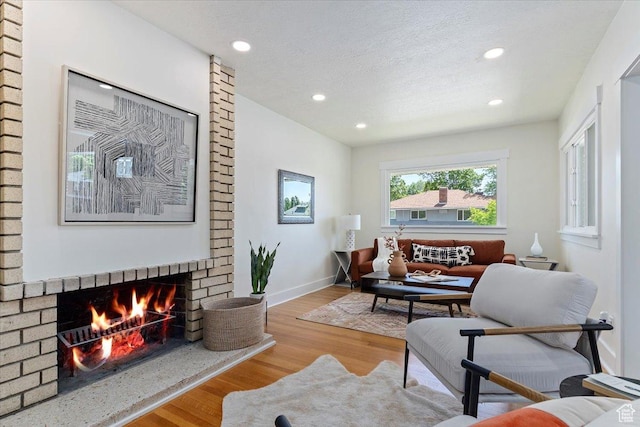 living room featuring wood finished floors, recessed lighting, a fireplace, and baseboards