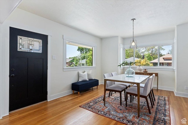 dining area with wood finished floors, a textured ceiling, and baseboards
