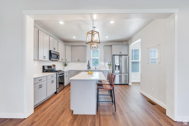 kitchen featuring stainless steel appliances, baseboards, a breakfast bar area, tasteful backsplash, and recessed lighting