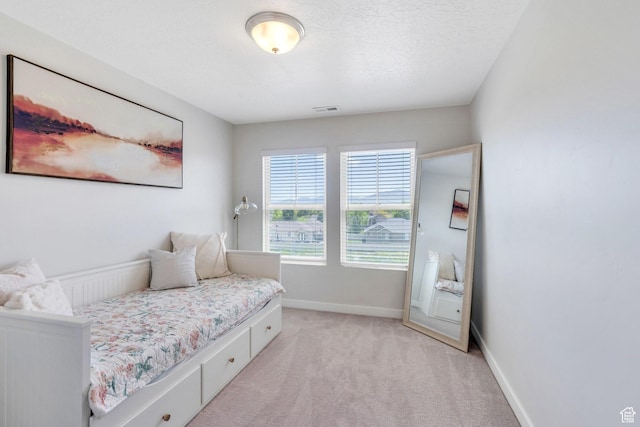 bedroom with light colored carpet and baseboards