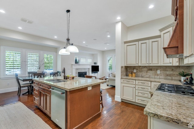kitchen featuring appliances with stainless steel finishes, a sink, open floor plan, dark wood-type flooring, and cream cabinetry