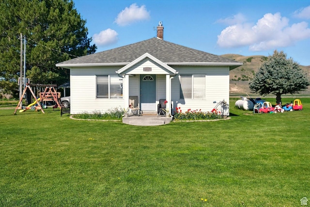 1317 S 400 E, Trenton, UT 84338 - view of front facade featuring a playground, a front yard, roof with shingles, and a chimney