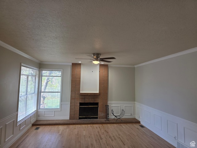 22 Snowstar Ln, Sandy, UT 84092 - unfurnished living room with a textured ceiling, a ceiling fan, wood finished floors, a brick fireplace, and crown molding