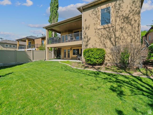 rear view of property with a balcony, french doors, a patio area, and stucco siding