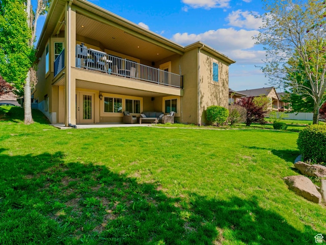 rear view of house with a balcony, stucco siding, a lawn, and an outdoor living space