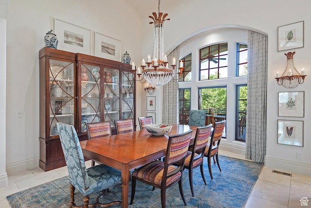 tiled dining room featuring a chandelier, arched walkways, baseboards, and a towering ceiling