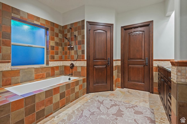 full bath with tile walls, wainscoting, tiled shower / bath, and vanity