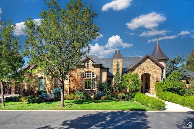 view of front of property with stone siding, a front lawn, and a chimney