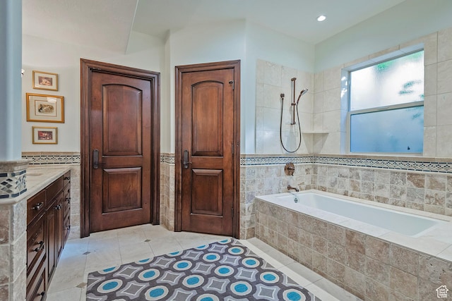 bathroom featuring tile walls, tile patterned flooring, a wainscoted wall, tiled shower / bath combo, and vanity