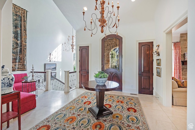 foyer featuring a chandelier, light tile patterned floors, a towering ceiling, and baseboards