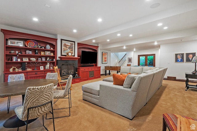 living room with light carpet, recessed lighting, a glass covered fireplace, and stairs