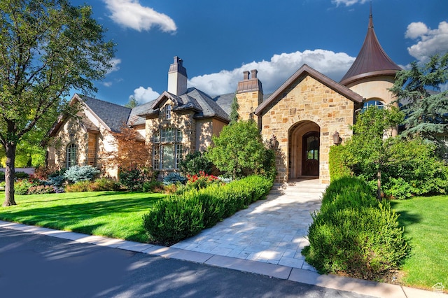 view of front facade with stone siding, a front lawn, and a high end roof