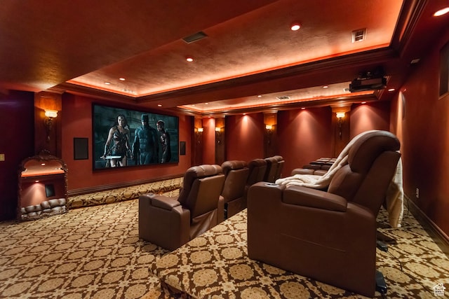 carpeted cinema room featuring a raised ceiling, baseboards, crown molding, and recessed lighting