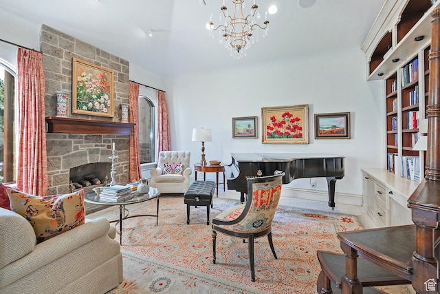 living room featuring baseboards, a chandelier, and a stone fireplace