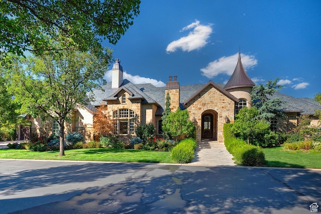 view of front of home featuring stone siding, a front lawn, and a chimney