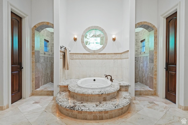 full bathroom with a garden tub, a walk in shower, marble finish floors, and baseboards