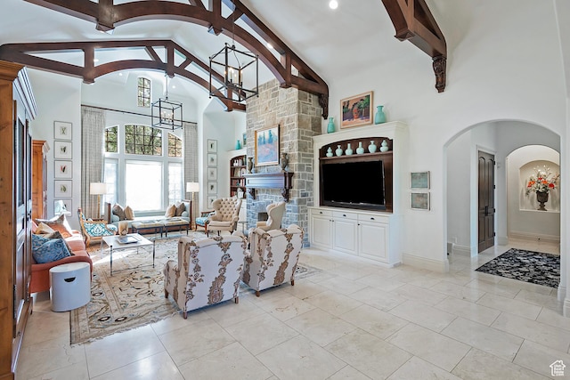 living area featuring a chandelier, high vaulted ceiling, arched walkways, beamed ceiling, and a fireplace