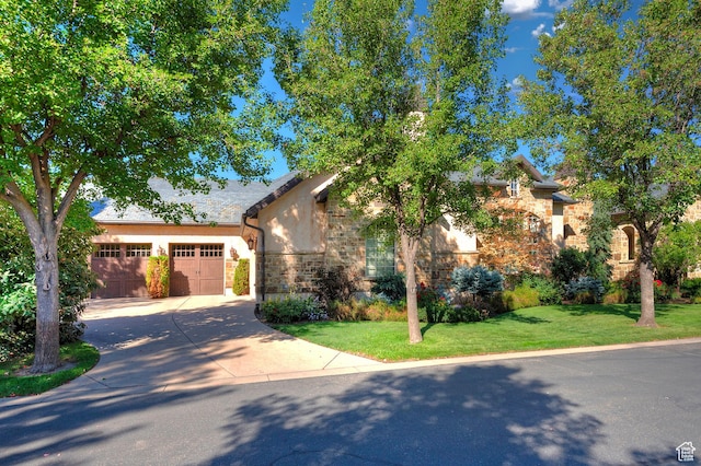 view of front of property with concrete driveway, stone siding, a front yard, stucco siding, and an attached garage