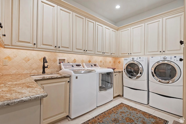 laundry area with washer and clothes dryer, light tile patterned floors, and cabinet space