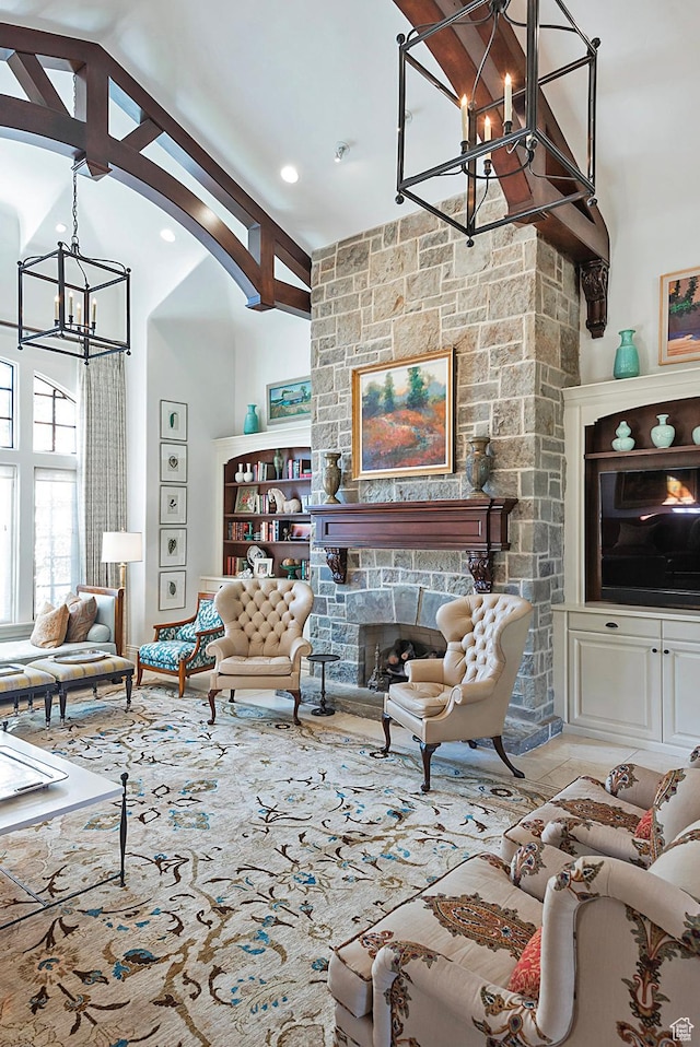 living area featuring a chandelier, a stone fireplace, and high vaulted ceiling