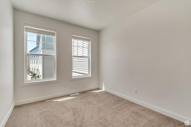 carpeted empty room featuring baseboards