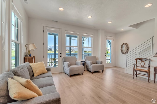 living area with healthy amount of natural light, a water view, recessed lighting, light wood-style flooring, and baseboards