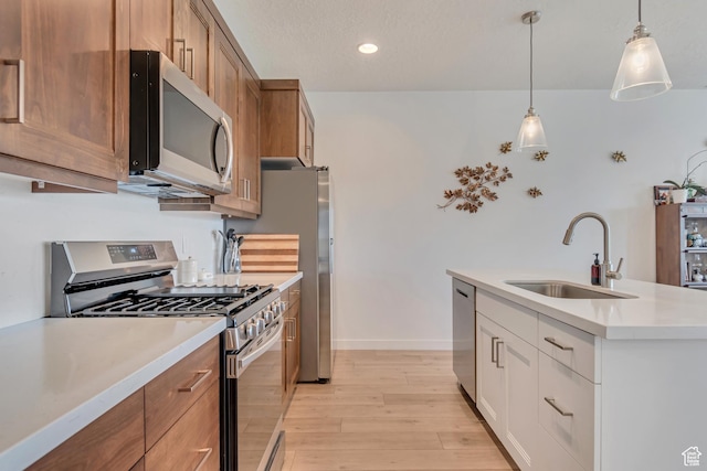 kitchen featuring stainless steel appliances, a sink, light wood-style floors, brown cabinets, and light countertops