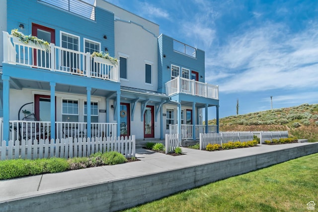 townhome / multi-family property with stucco siding, a porch, and a balcony