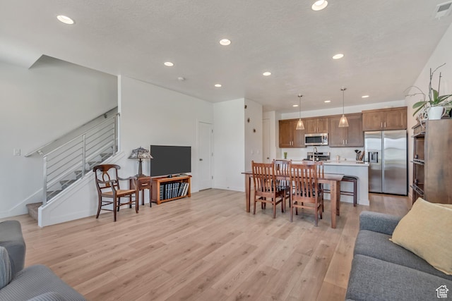 living room with recessed lighting, light wood finished floors, and stairs