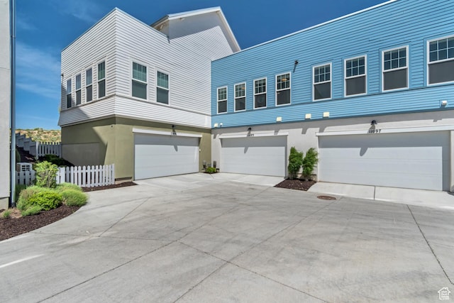 view of front of property featuring a garage, fence, concrete driveway, and stucco siding