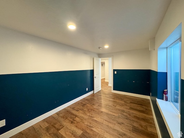empty room featuring wood finished floors, recessed lighting, and baseboards