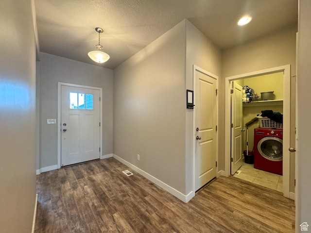foyer entrance with washer / dryer, wood finished floors, and baseboards