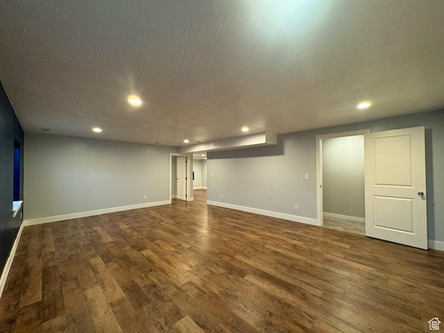 finished below grade area featuring dark wood-style flooring, recessed lighting, baseboards, and a textured ceiling