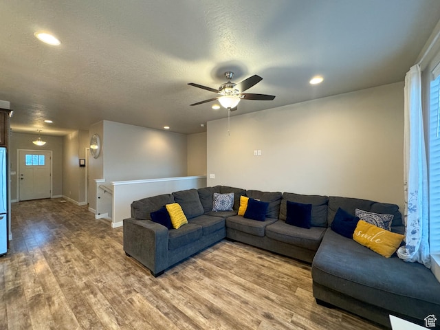 living area featuring light wood finished floors, a ceiling fan, healthy amount of natural light, recessed lighting, and a textured ceiling