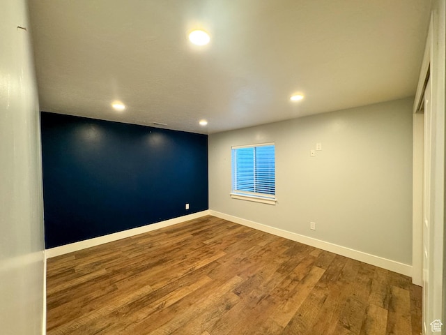 unfurnished room with recessed lighting, wood finished floors, and baseboards
