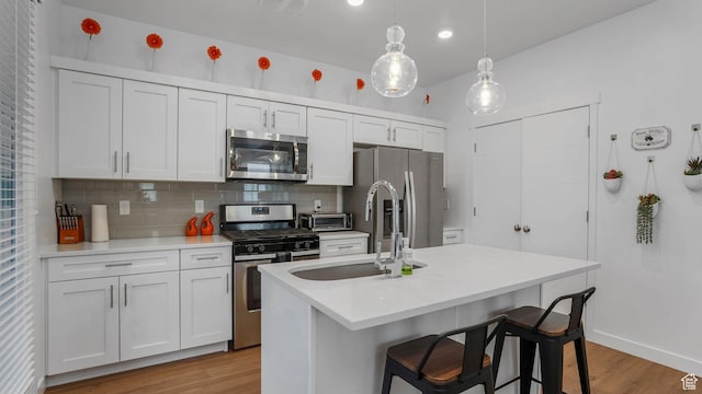 kitchen featuring appliances with stainless steel finishes, a sink, light wood finished floors, light countertops, and recessed lighting