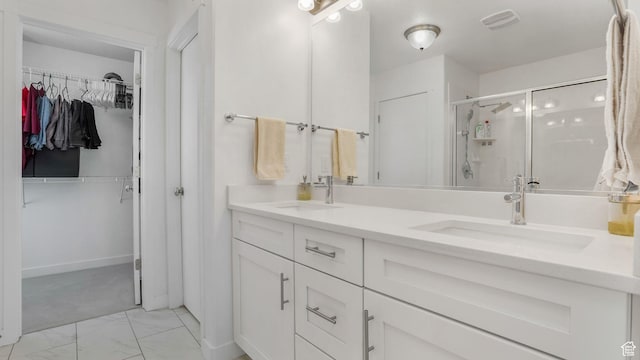 full bath with a shower stall, marble look tile flooring, double vanity, and a spacious closet