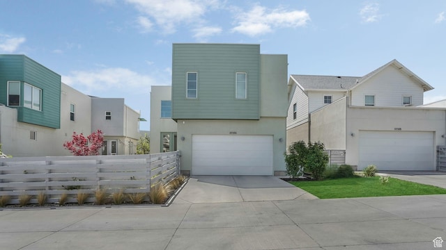 modern home with stucco siding, fence, concrete driveway, and an attached garage