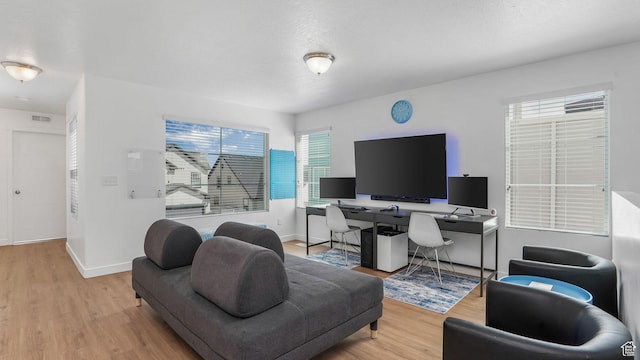 living room featuring wood finished floors, an office area, plenty of natural light, and baseboards