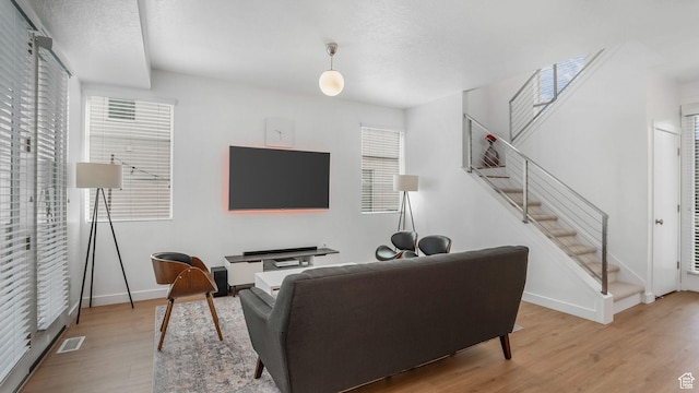 living area with wood finished floors, baseboards, and stairway