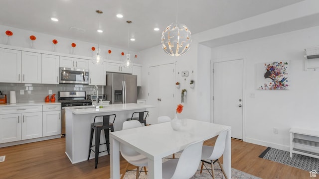 dining area with light wood-style flooring, recessed lighting, a chandelier, and baseboards