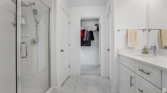full bathroom featuring a shower stall, marble finish floors, a walk in closet, and vanity