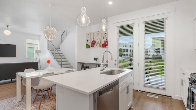 kitchen with dishwasher, a sink, light wood finished floors, and light countertops