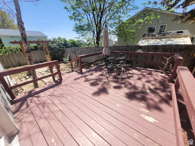 wooden terrace with outdoor dining area and a fenced backyard