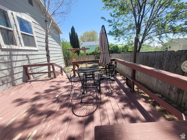 wooden terrace featuring outdoor dining space and a fenced backyard