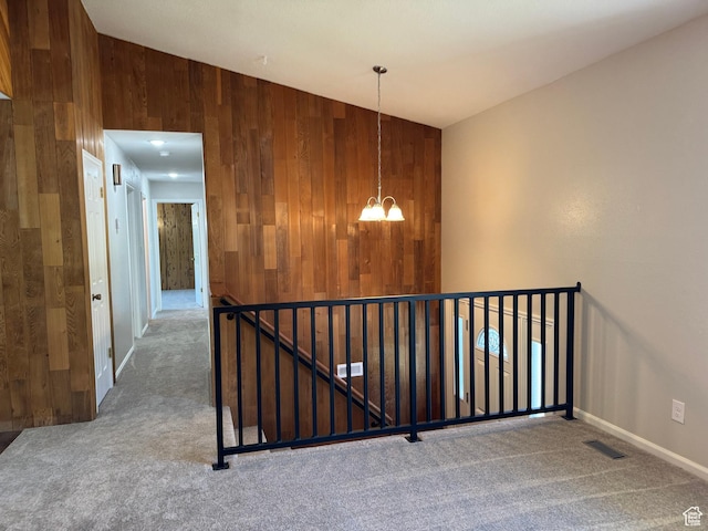 staircase with carpet flooring, a chandelier, wooden walls, and baseboards