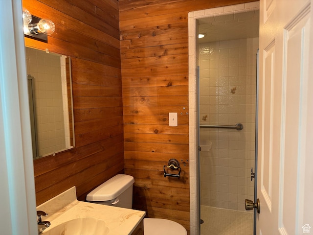 bathroom with toilet, vanity, a stall shower, and wooden walls