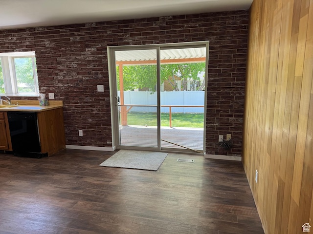 entryway with dark wood-type flooring, a sink, and brick wall